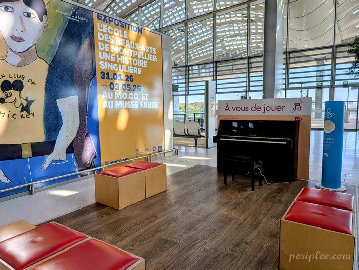 Intérieur de la Gare Montpellier Sud de France, espace d’attente moderne avec exposition artistique et piano en libre accès