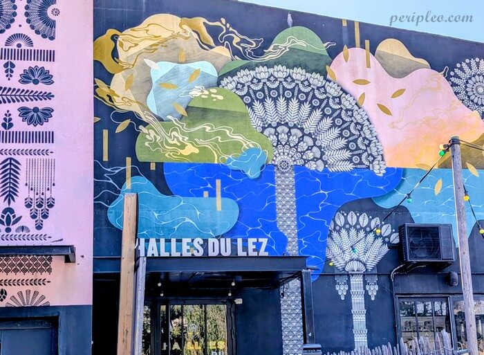 Grande fresque murale colorée de Koralie ornant les Halles du Lez du Marché du Lez, haut lieu du street art et de la gastronomie à Montpellier