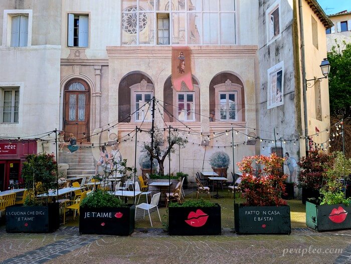 Fresque monumentale en trompe-l’œil signé Mad'Art Place Saint-Roch à Montpellier, façade peinte et terrasse au cœur du centre historique sud
