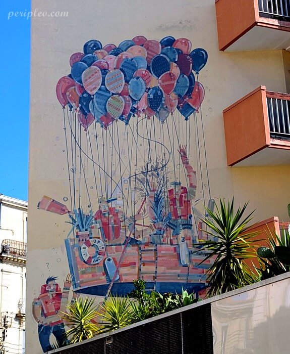Street art Rue d'Alsace à Montpellier, grande fresque murale représentant une ville suspendue à des ballons colorés d'ADEC en partenariat avec l'association LineUp dans le Quartier Méditerranée