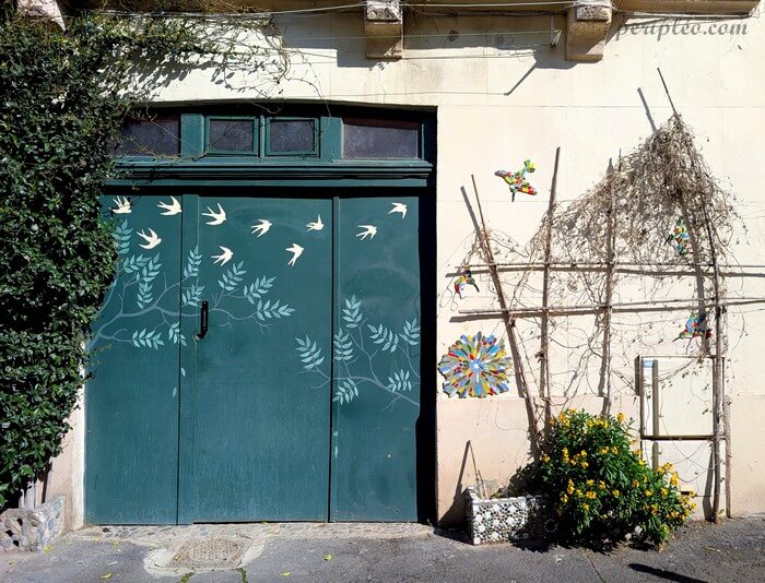 Porte décorée d’un street art végétal dans la Rue de Barcelone à Montpellier, avec oiseaux blancs et motifs naturels