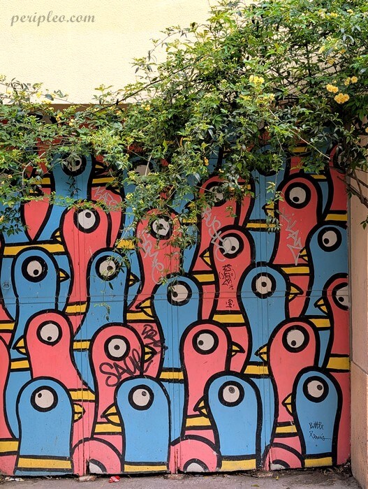 Street art Rue Lamartine à Montpellier, fresque colorée de Little Lewis représentant une foule d’oiseaux graphiques dans le Quartier Méditerranée