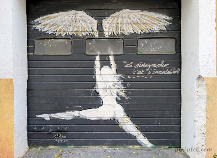 Street art Rue de Lorraine à Montpellier, fresque d’une danseuse suspendue sous deux ailes avec citation poétique sur une porte du Quartier Méditerranée