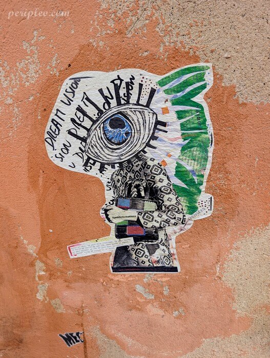 Street art Rue de Lorraine à Montpellier, collage artistique représentant un personnage à tête d’œil bleu sur un mur du Quartier Méditerranée