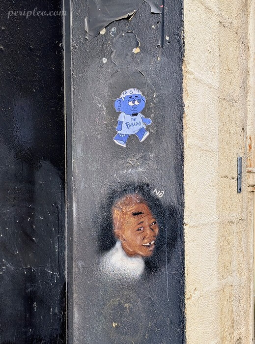 Petite illustration de Quincy Gane Rue du Plan d’Agde à Montpellier et portrait peint par Nô d'un petit garçon souriant sur une façade du centre historique sud