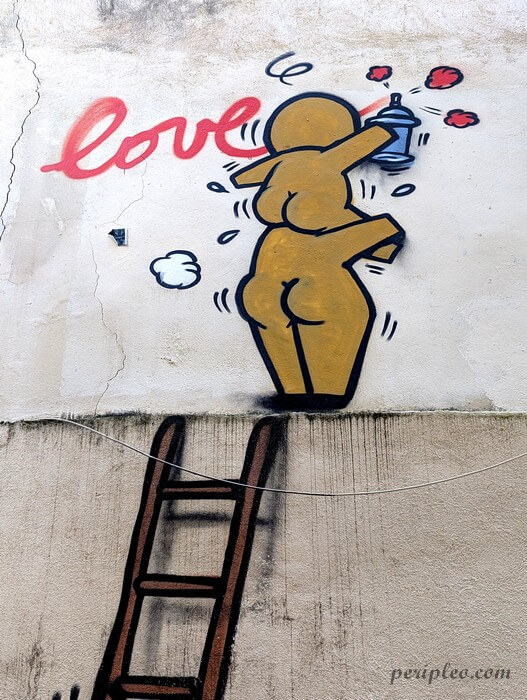 Street art humoristique de Jace Rue du Plan de l’Olivier à Montpellier représentant un gouzou peignant le mot « Love » à la bombe aérosol sur un mur du centre historique nord