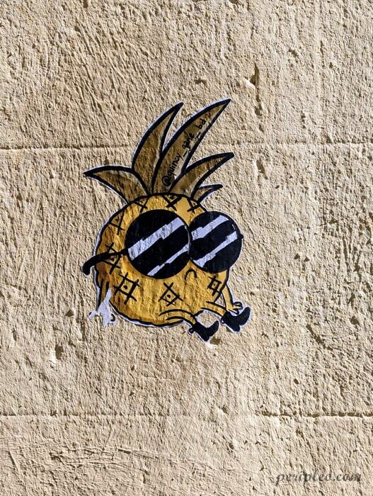 Street art de Quincy Gane Rue Roucher à Montpellier, collage d’un ananas stylisé portant des lunettes dans le centre historique sud