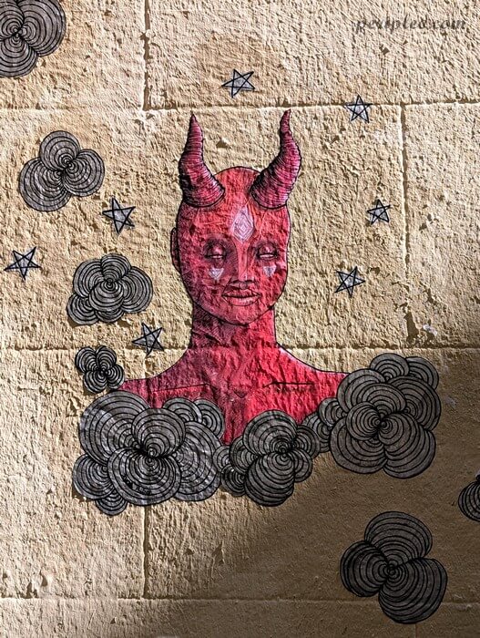 Street art Rue Roucher à Montpellier, collage artistique représentant un personnage rouge entouré de motifs floraux dans le centre historique sud