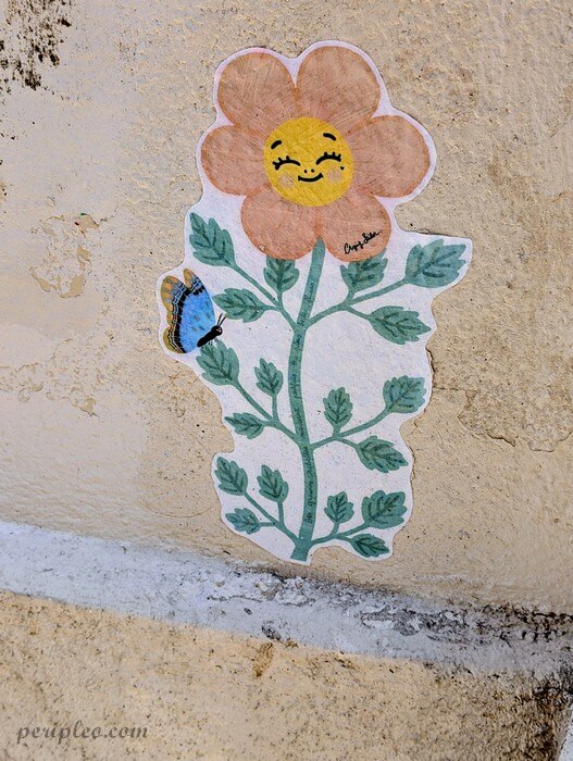 Street art de Crying Sailor Rue Roucher à Montpellier, collage d’une fleur souriante et d’un papillon sur un mur du centre historique sud
