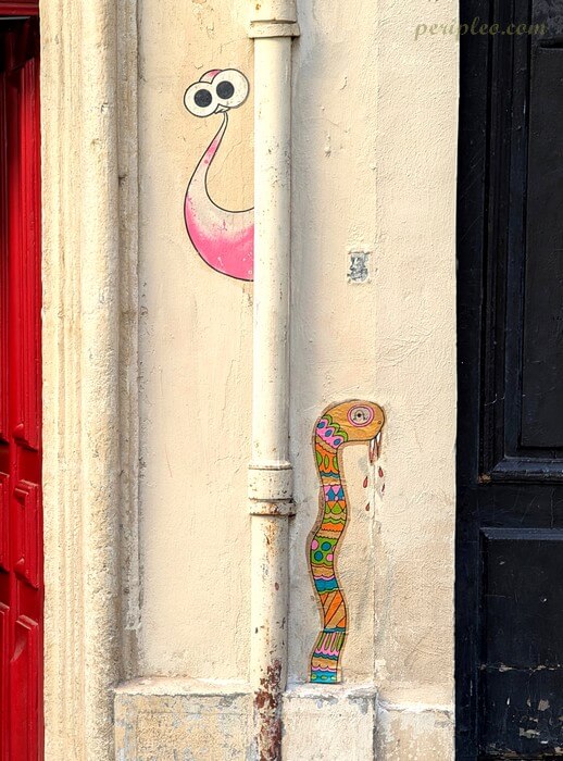 Petites œuvres de street art Rue de l’Université à Montpellier représentant des personnages colorés et fantaisistes intégrés au mobilier urbain du centre historique nord