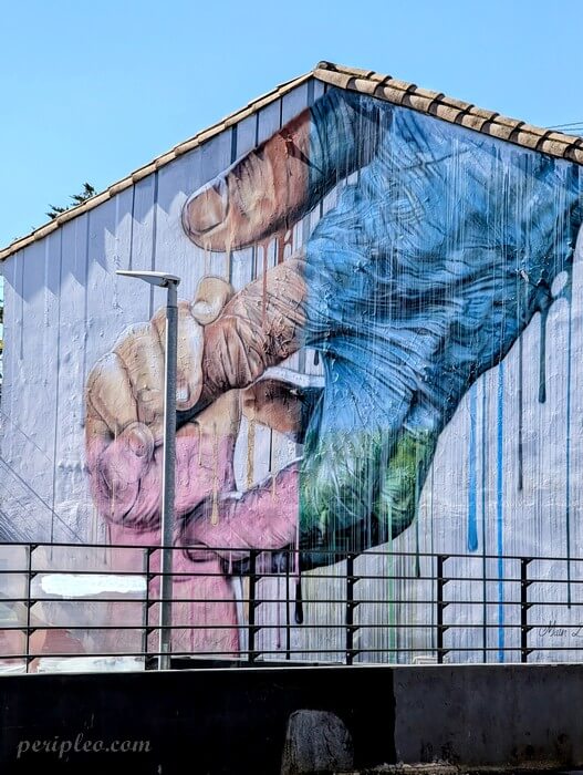 Fresque de street art de Seno représentant deux mains se rejoignant sur un bâtiment de l’Avenue de Toulouse à Montpellier
