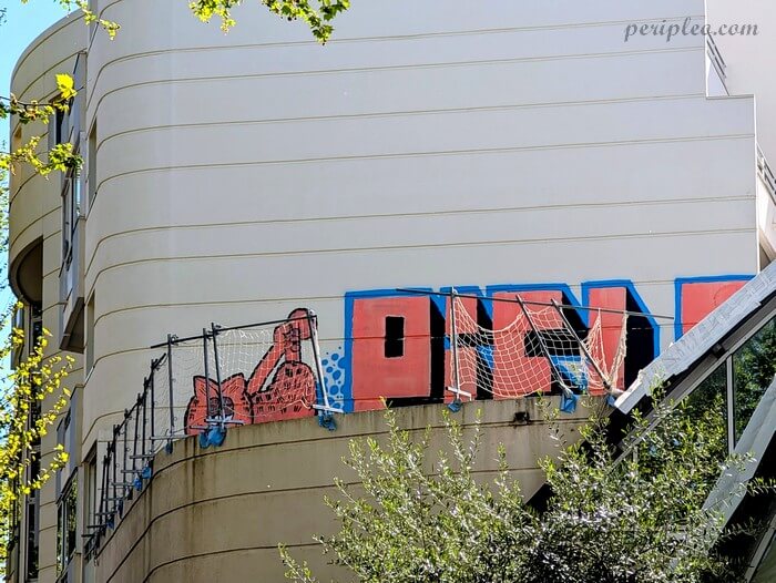 Œuvre de street art sur le Boulevard de Strasbourg à Montpellier, mêlant lettrage graffiti coloré et filet de football sur une façade urbaine.