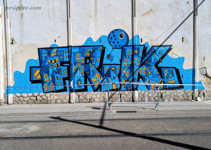 Street art bleu représentant une ville imaginaire aux fenêtres illuminées sur le Boulevard de Strasbourg à Montpellier, œuvre de FRIK et Oups