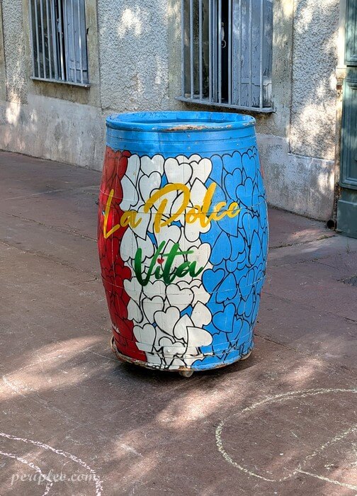 Street art Place des Beaux-Arts à Montpellier, tonneau décoré par Sunra aux couleurs bleu, blanc et rouge, recouvert de cœurs et du message « La Dolce Vita »