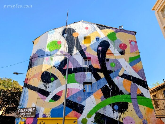 Street art Place Rondelet à Montpellier avec grande fresque abstraite et colorée de Mist recouvrant une façade du centre-ville moderne