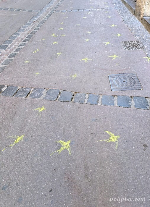Street art Rue de l'Aiguillerie à Montpellier, envolée de petites hirondelles jaunes peintes au sol, une intervention artistique discrète qui accompagne les pas des promeneurs dans le centre historique nord