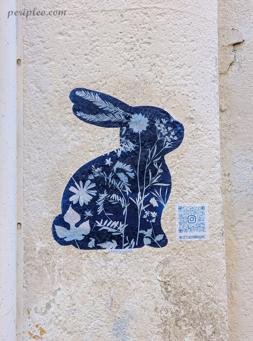 Street art Rue de l'Aiguillerie à Montpellier, collage de LittleCyanoGirl représentant un lapin bleu aux motifs floraux dans le centre historique nord