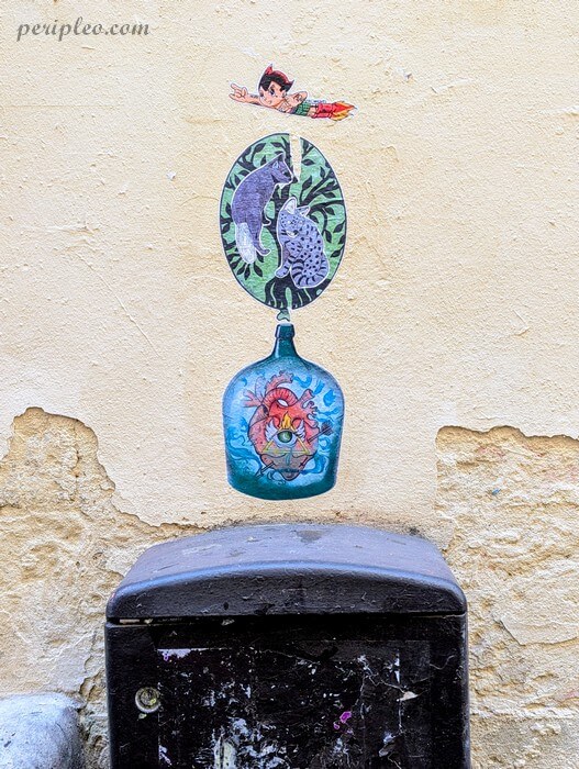 Street art Rue de la Carbonnerie à Montpellier, collage mêlant un cœur anatomique dans une bouteille, deux félins dans un médaillon végétal et un petit personnage volant dans le centre historique nord