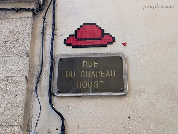 Street art Rue du Chapeau Rouge à Montpellier, mosaïque en pixel art de Mifamosa représentant un chapeau rouge installée au-dessus de la plaque de rue