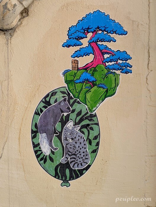 Street art signé Max Marlou et Mdlf Antho Rue Chrestien à Montpellier, assemblage de collages mêlant un renard noir, un chat sauvage et un îlot végétal surmonté d'un arbre bleu aux allures fantastiques sur un mur du centre historique nord