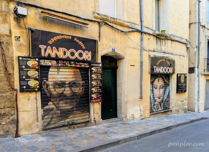 Street art Rue des Écoles Laïques à Montpellier, rideaux métalliques du restaurant Tandoori ornés de portraits en trompe-l'œil dans le centre historique nord