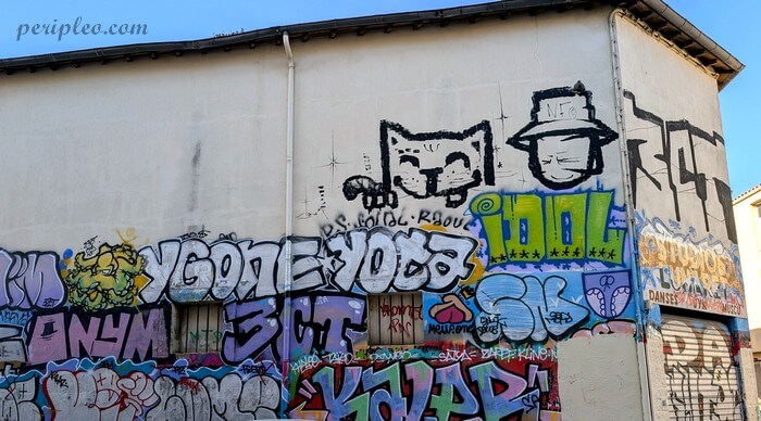 Street art Rue Proudhon dans le Quartier des Beaux-Arts à Montpellier, façade entièrement recouverte de graffitis où se mêlent lettrages colorés, personnages stylisés et chats malicieux