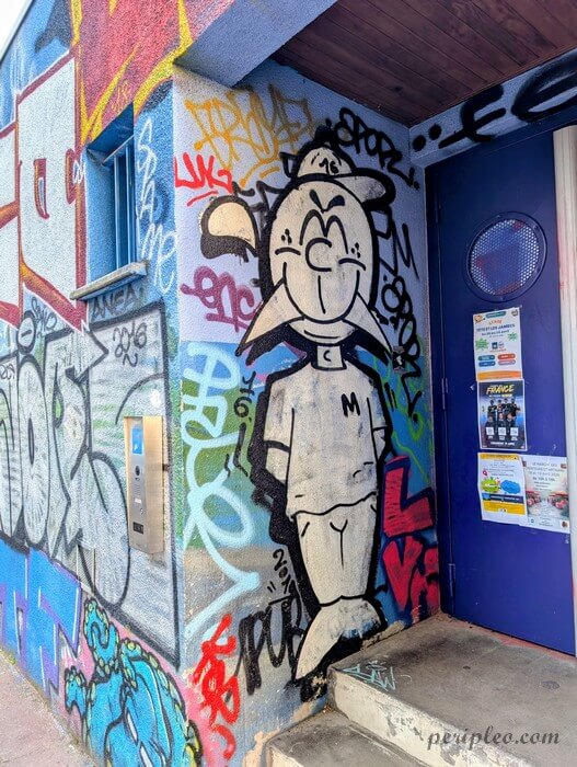 Street art représentant un personnage de bande dessinée en noir et blanc entouré de graffitis colorés dans la Rue de la Substantion à Montpellier