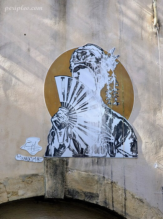 Street art de Sunny Jim Rue de la Verrerie à Montpellier, collage en noir et blanc d'un personnage masqué dissimulé derrière un éventail dans le centre historique nord