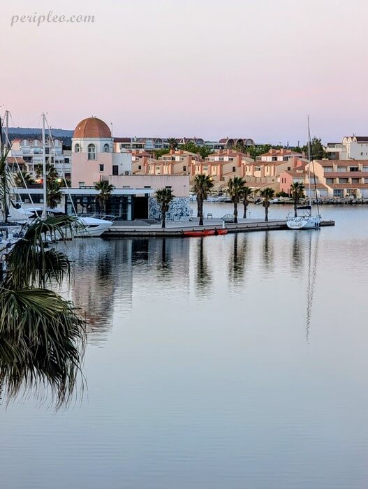 Port de Gruissan et Capitainerie au coucher du soleil avec palmiers et reflets sur la marina