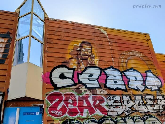 Street art au Gymnase Louis Nègre à Montpellier, fresque mêlant portrait réaliste aux teintes sépia et imposants lettrages graffiti colorés