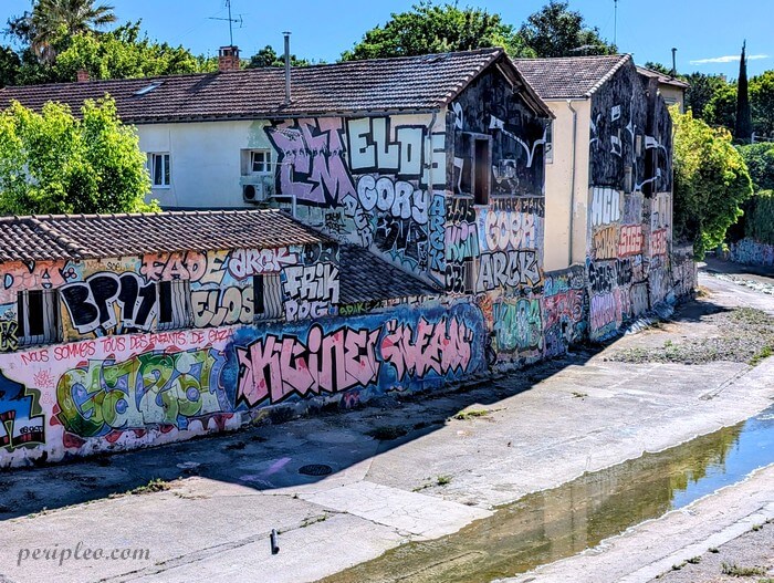 Street art le long du canal du Verdanson à Montpellier près du Stade Philippidès, mur couvert de graffitis colorés sur plusieurs façades