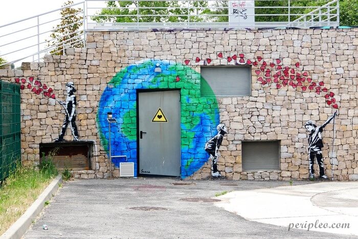 Street art au Parc des Berges du Lez à Montpellier, œuvre engagée de Sunra représentant deux enfants de part et d'autre d'une planète Terre, reliés par une envolée de cœurs rouges