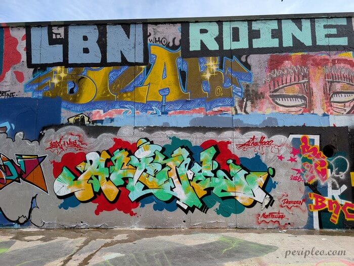 Street art Quai du Verdanson à Montpellier, enchevêtrement de lettrages graffiti aux couleurs éclatantes, signatures d'artistes et visages stylisés