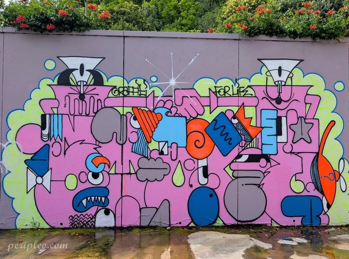 Street art Quai du Verdanson à Montpellier, fresque graphique aux formes géométriques et personnages fantaisistes, dominée par des tons roses, bleus et orange
