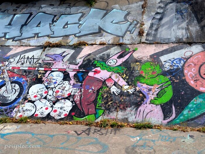 Street art Quai du Verdanson à Montpellier, fresque décalée mettant en scène un clown, des créatures fantastiques et des personnages aux visages expressifs