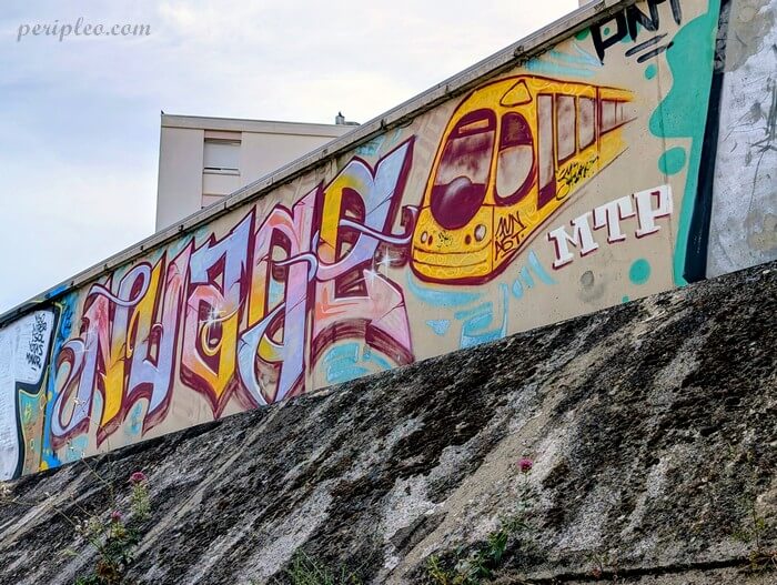 Street art Quai du Verdanson à Montpellier, graffiti coloré représentant une rame du tramway montpelliérain intégrée à un lettrage XXL