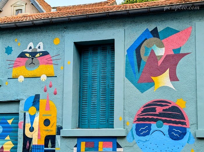 Street art de l'Atelier Parcours Rue Marcel de Serres à Montpellier, façade colorée mêlant personnages fantaisistes et formes géométriques dans un univers graphique ludique